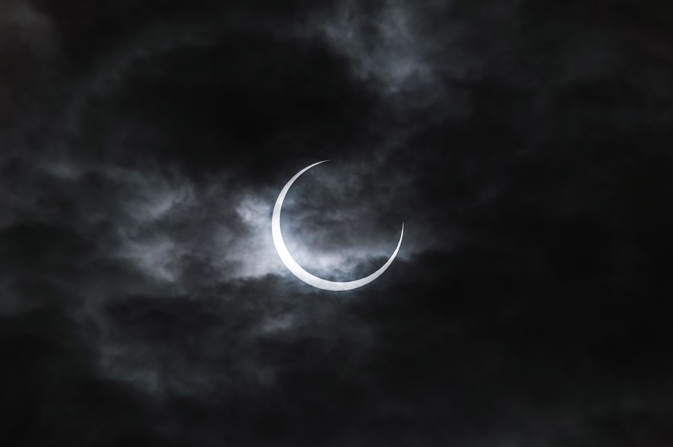 Solar Eclipse Crescent Wallpaper Through Dark Clouds